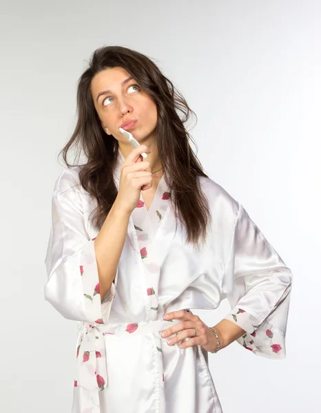 Mulher em peignoir com escova de dentes olhando para cima — Fotografia de Stock