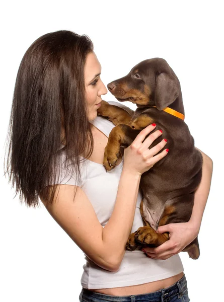 Brunette meisje op zoek naar haar puppy geïsoleerd op witte achtergrond — Stockfoto