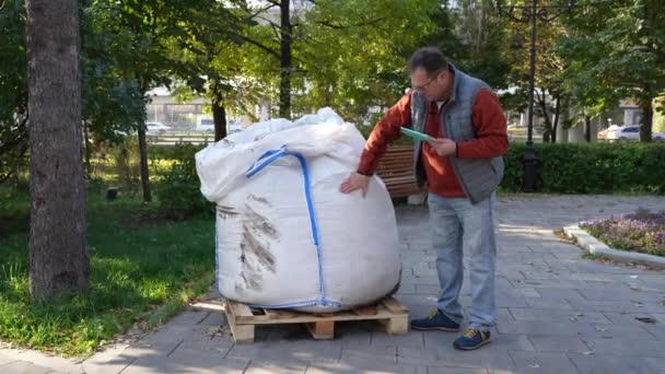 Homme avec une tablette vérifie la qualité du contenu d'un grand sac blanc — Video