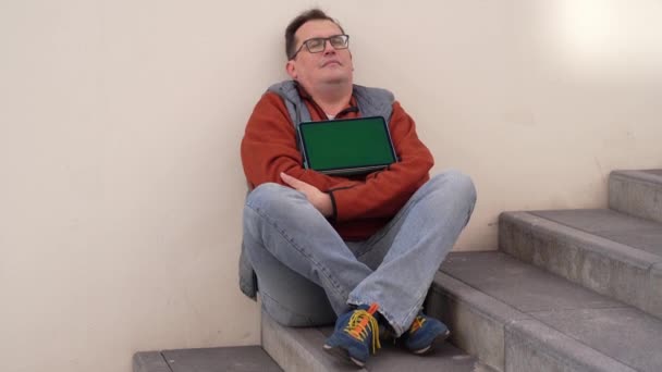 Ontslagen blanke mannelijke werknemer zittend op de trap in depressie met groen scherm op tablet computer. — Stockvideo