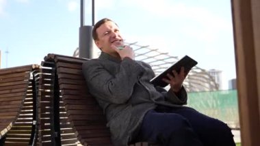 Tabletli olumlu iş adamı koltukta dönüyor