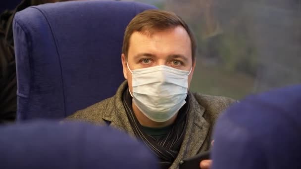 Cansado homem vestindo uma máscara médica passeios em trem suburbano — Vídeo de Stock