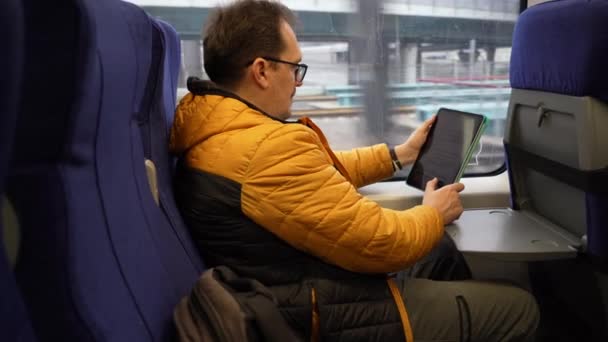 Hombre leyendo un libro electrónico en un vagón de tren en movimiento — Vídeo de stock