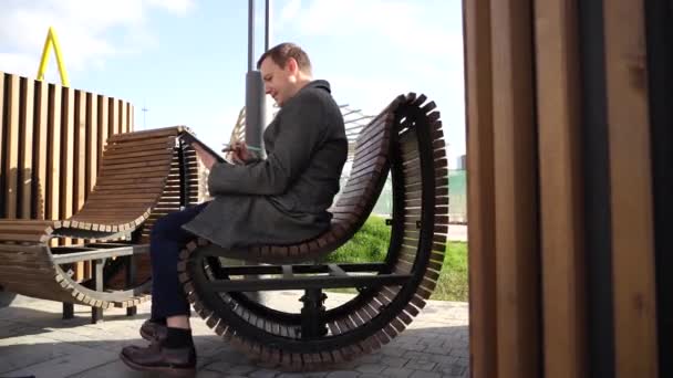 Позитивний бізнесмен з планшетом обертається на кріслі — стокове відео