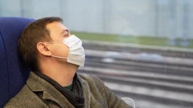 Banliyö treninde tıbbi maske takan yorgun bir adam.