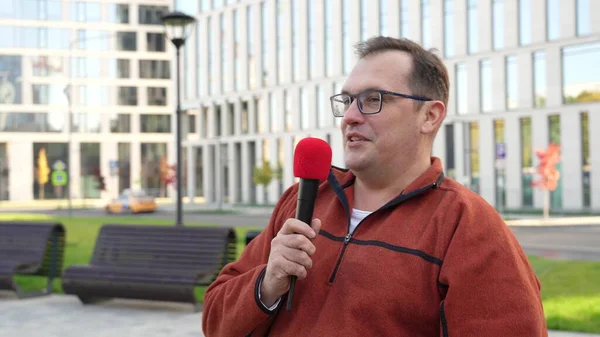 Periodista adulto con micrófono trabajando en el parque de otoño. — Foto de Stock