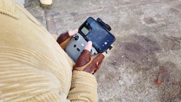 Remote control of consumer quadcopter in male hands wearing fingerless gloves — Stock Video
