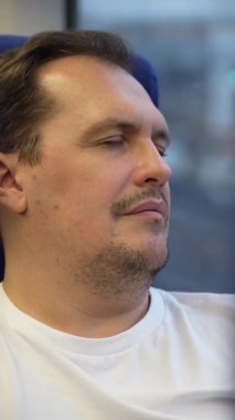 Yorgun adam banliyö trenine biniyor.