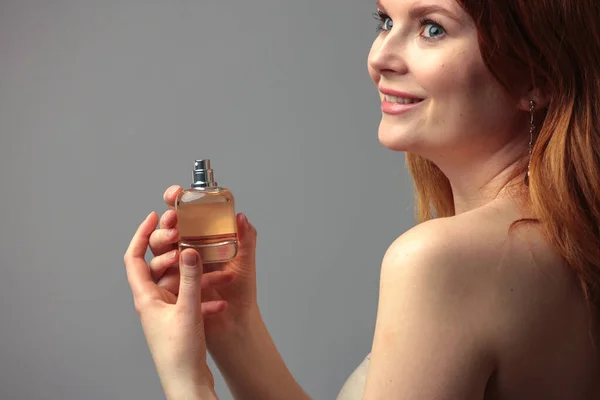 Perfume bottle in hands of woman