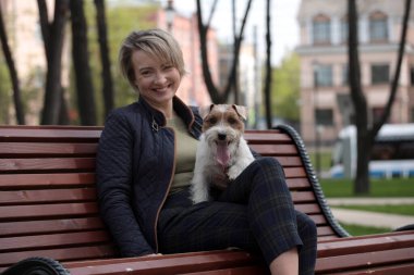 Beyaz Jack Russell Terrier 'larla parkta dinlenen çekici bir kadın. Aşk hikayesi.