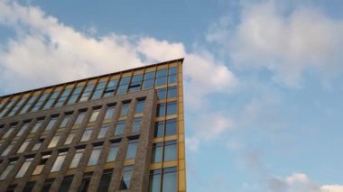 Yüksek katlı apartman cephesinin üstünde bulutlar dolaşıyor. Zaman aşımı