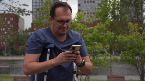Man Met Kruk Gele Koffer Gebruikt Smartphone Park — Stockvideo