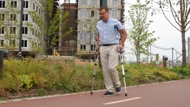 Hombre Guapo Caminando Sobre Muletas Parque Urbano — Vídeos de Stock