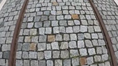 Turistler kaldırım taşları üzerinde tramvay rayları boyunca yürür