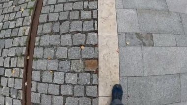 Turistler kaldırım taşları üzerinde tramvay rayları boyunca yürür