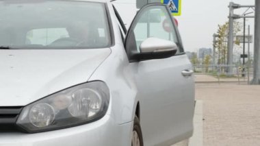 Adam cep telefonu, iletişim ya da internet uygulaması kullanarak kapıyı kapatıyor. Şehir caddesinde ya da otoparkta arabanın yanında duruyor. Araba paylaşımı, kiralama servisi veya taksi uygulaması.