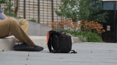 Adam dilenci çantasına para atıyor. Dilenci, zavallı, kaybolmuş turist konsepti. Siyah bağış çantası. Adam minnet jesti olarak ellerini kavuşturuyor..