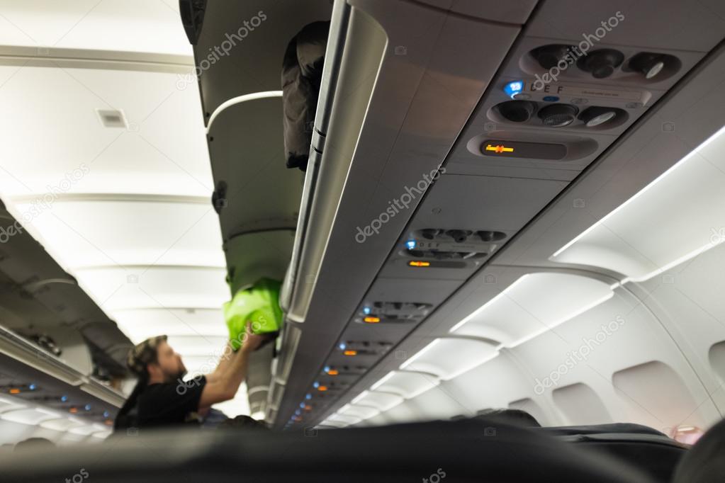 Puting away luggage in airplane.