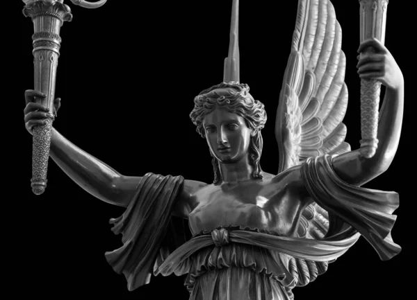 Egy szárnyas győzelmi istennő, Nika szobra. Szobor egy gyönyörű szent angyal szárnyakkal tartja fáklyák elszigetelt fekete háttér nyírás út — Stock Fotó