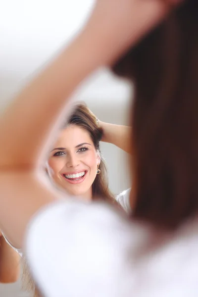 Happy woman looks at herself in the mirror — Stock Photo, Image