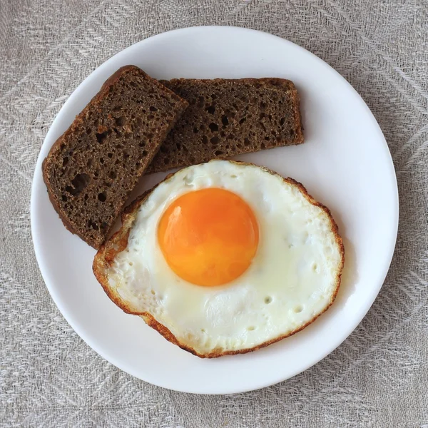 Fried egg and black bread — Stock Photo, Image