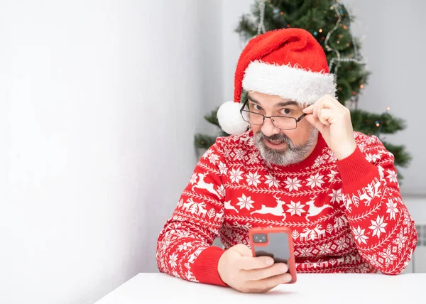 Człowiek Brodą Kapeluszem Mikołaja Trzyma Koncepcję Świątecznego Telefonu Komórkowego Puste — Zdjęcie stockowe