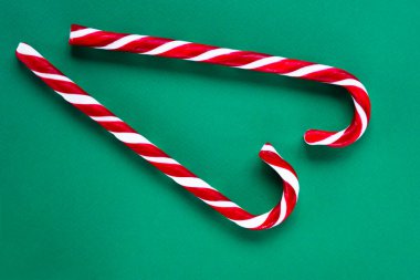 Yeşil arka planda kırmızı ve beyaz baston şekerler. Noel konsepti. Düz konum, üst görünüm, kopyalama alanı