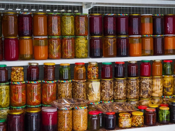 Preserved and fermented food. Assortment of jars with variety of pickled vegetables, mushrooms, fruits, jams on the shelves. Housekeeping, home economics, harvest preservation. Fermented food concept