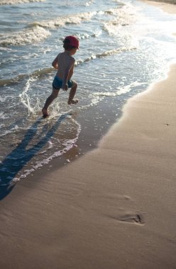 Kumsaldaki küçük çocuk. Mavi deniz ve gökyüzü. Seyahat, tatil ve macera konsepti. Yaz tatili