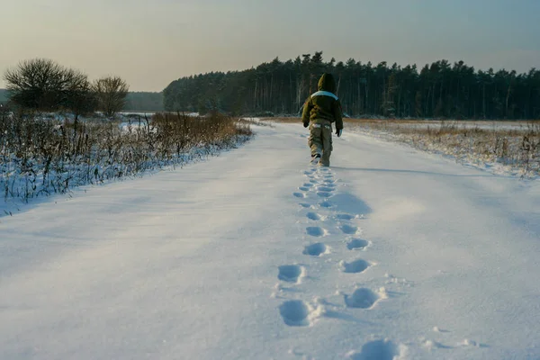 小さな男の子の後ろの自然を歩いて表示します 雪の中の足跡 健康的な生活 — ストック写真