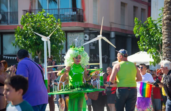Sitges, Katalonya, İspanya - 11 Haziran 2017: Sitges, İspanya - 11 Haziran 2017: Rüzgar jeneratörleri türbinli yeşil kostüm giyen katılımcı eşcinsel gururu. Rüzgar jeneratörlü harika bir manzara. Gelecekteki temiz alternatif enerji kavramı