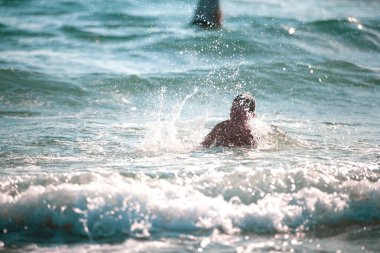Sahilde küçük bir çocuk, yaz zamanı dalgalarla oynuyor. Rahatlama ve sağlıklı bir yaşam tarzı. Yaz tatili, sağlık gelişimi