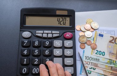 Hesap makinesi, para, kalem ve zarf masada. Para saymak. Emeklilik hesabı.