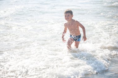 Sahilde küçük bir çocuk, seçici bir odak noktası. Yaz zamanı. Rahatlama ve sağlıklı yaşam tarzı kavramı