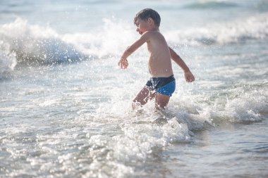 Sahilde küçük bir çocuk, seçici bir odak noktası. Yaz zamanı. Rahatlama ve sağlıklı yaşam tarzı kavramı