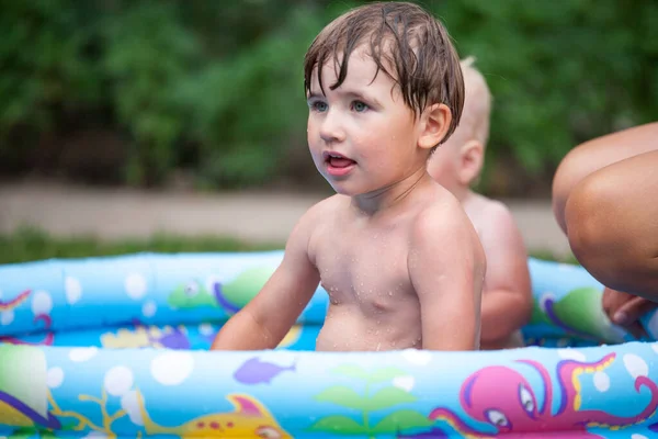 屋外の膨脹可能なプールの小さい男の子 インフレータブル屋外プールでリラックスしている2人の子供 夏休みと健康的なライフスタイルのコンセプト — ストック写真