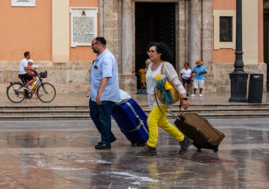 Valencia, İspanya - 06 Ağustos 2019: Bakire Meydanı 'nda bavullu turistler. Valencia 'nın merkezinde, ünlü tarihi binalar ve açık hava kafeleriyle çevrili canlı bir meydan.