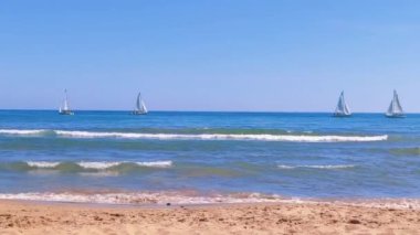 Woman feet walking along sea water waves on sandy beach. Female on summer travel vacation, slow motion. Sitges beach on a sunny day, Barcelona, Spain. Concept of summer vacation