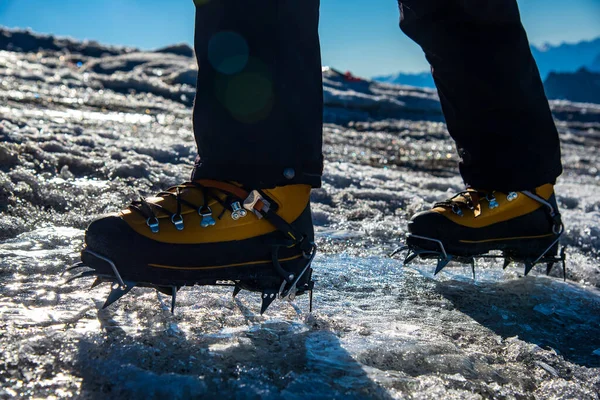 A mountaineering boot equipped with a traditional 10-point glacier trekking crampon. Mountaineer ascending up on the summit.International Mountaineering Day - 8 August