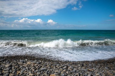 Restless Black Sea, pebble beach and blue background of the sky