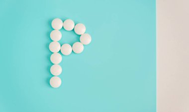 Letter P made from white pills on a blue background. White medical pills. Macro top view with copy space. Health care and pills concept, pharmaceutical, disease prevention
