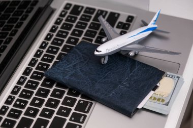 Top view of laptop computer, passport with US dollar banknotes and credit card, airplane.Travel and vacation, planning trip in the office or home, holiday tourism, agency tour