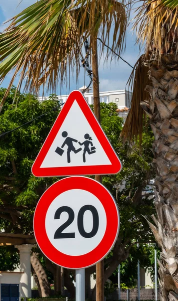 Combination of international traffic signs \'Speed limit\' (20 km/hour) and \'Children crossing\'. Children Crossing Road Sign-School Crossing Sign
