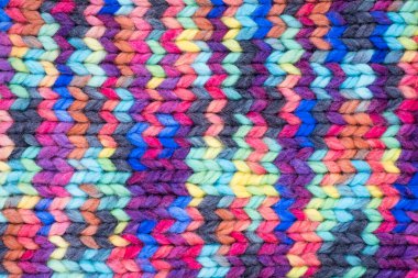 Woolen knitted background with a relief pattern. The texture of the fabric of a sweater, blanket or scarf is large. Wool, manual typewriter, handmade. Wildly Variegateds color