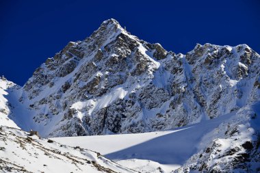 Winter snowy mountains. High snowy sunlight mountain and blue sky at winter, high contrast. Caucasus Mountains. Aerial view to the mountains. Alpine climbing