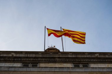 Flag of Spain and flag of Catalonia side by side in the wind in Barcelona.