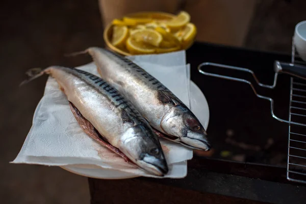 Mackerel fish on a wooden cutting board, top view. The process of cooking fish outdoors. Tasty and fresh food, picnic, party, outdoor recreation. Cooking on the nature