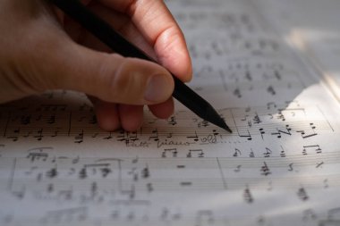 Bir müzisyenin ya da bestecinin yakın çekimi bir parça müzik yazar. Konservatuar, müzik, besteci, notalar, dersler, sanatsal yaşam konsepti. Notaları ve kalemi olan sayfa.