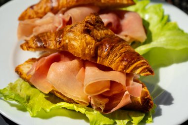 Jambonlu kruvasan sandviçi (jambonlu, jambonlu, jambonlu) ve marullu. Lezzetli aperatifler, mezeler, tapalar. Kahvaltıda. Yolculuk için fast food