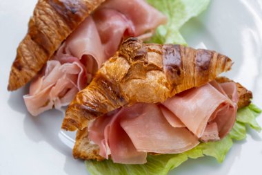 Jambonlu kruvasan sandviçi (jambonlu, jambonlu, jambonlu) ve marullu. Lezzetli aperatifler, mezeler, tapalar. Kahvaltıda. Yolculuk için fast food